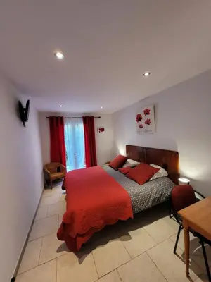 a bedroom with a bed with red pillows and a table at le clos des sources in Saint-Chamas
