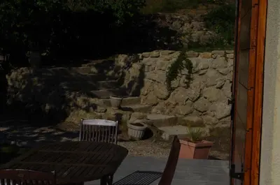 a patio with a table and chairs and a stone wall at le clos des sources in Saint-Chamas