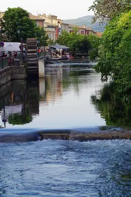 a river with a bridge in the middle of a city at Mas et Gite de la Picholine in LʼIsle-sur-la-Sorgue
