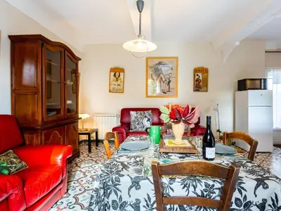 a living room with a table and a red couch at Holiday Home L'Olivier by Interhome in Ménerbes