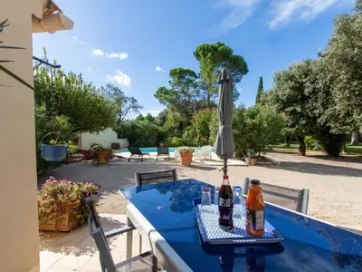 a table with an umbrella and two bottles on it at Holiday Home Les Amandiers by Interhome in Mazan