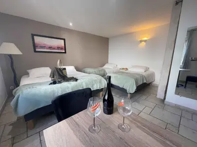 a hotel room with two beds and a table with wine glasses at Les Loges du Luberon in Coustellet