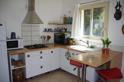 a kitchen with white cabinets and a wooden counter top at Chez MiLy in Sénas