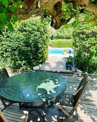 a glass table with two chairs and a pool at Mas des Prevots B&B in Noves
