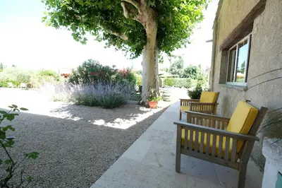 two benches sitting next to a building with a tree at Semi-detached provencal farm with swimming pool in Orgon