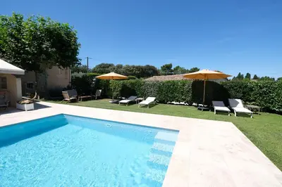 a swimming pool with chairs and umbrellas in a yard at Semi-detached provencal farm with swimming pool in Orgon