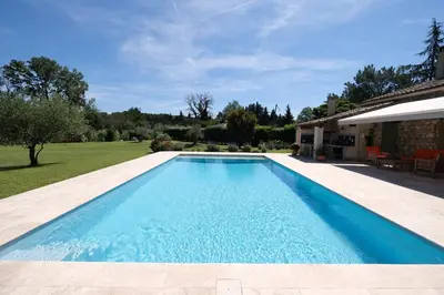 a swimming pool in a yard next to a house at Semi-detached provencal farm with swimming pool in Orgon