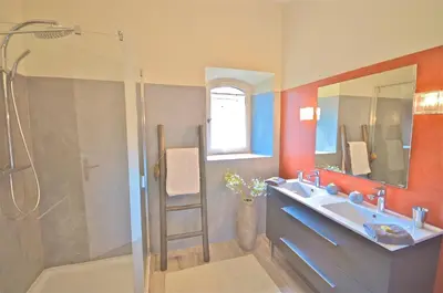 a bathroom with a sink and a shower with a mirror at Ferme St Roch in Robion en Luberon