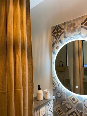 a bathroom with a shower curtain and a mirror at Le cœur de Lourmarin Loulou en Luberon in Lourmarin