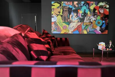 a red couch in a living room with a tv at La Maison d'Aix 1785 - Hôtel Particulier & Spa in Aix-en-Provence