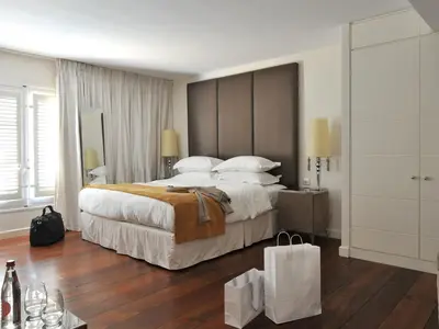 a hotel room with a large bed and a shopping bag at La Maison d'Aix 1785 - Hôtel Particulier & Spa in Aix-en-Provence