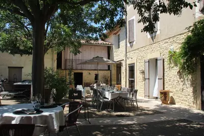 an outdoor restaurant with tables and chairs and a tree at le clos du Patre in Caromb