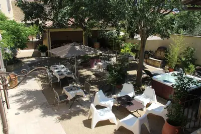 an outdoor patio with tables and chairs and a tree at le clos du Patre in Caromb