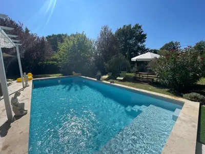 a swimming pool with blue water in a yard at La belle histoire Gîte Montmirail in Bédoin