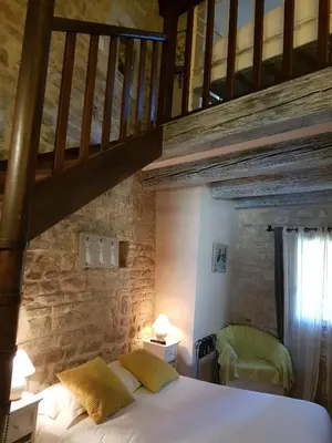 a bedroom with a bed with a stone wall at Le Crillon in Murs