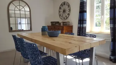 a dining room table with chairs and a clock on the wall at Mas des Mûriers in Saumane-de-Vaucluse