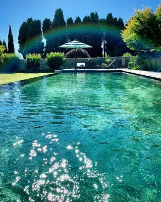 a pool of blue water with a rainbow in the background at Le Pavillon de Galon in Cucuron
