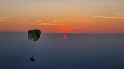 a person flying a kite in the sky at sunset at La belle histoire Gîte Ventoux in Bédoin