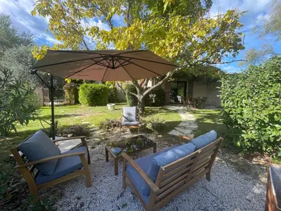 a patio with two chairs and an umbrella at La belle histoire Gîte Ventoux in Bédoin