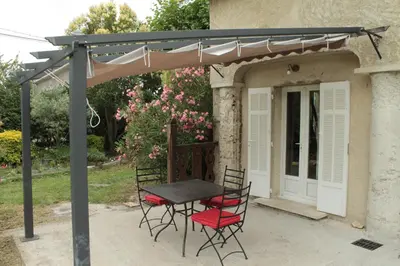 a patio with a table and chairs under a pergola at Mas Michel et Josiane in Monteux