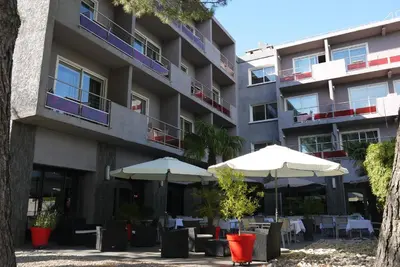 an apartment building with tables and umbrellas at Le Safari Hotel Restaurant in Carpentras