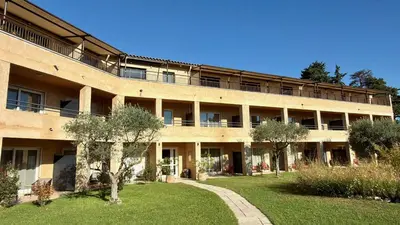 a large building with a garden in front of it at Hôtel La Perna in Pernes-les-Fontaines