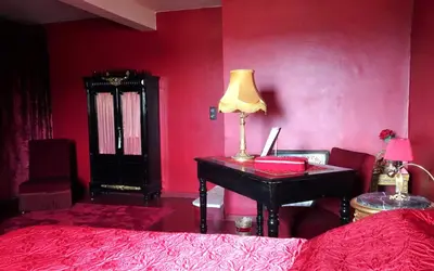 a bedroom with a desk and a red wall at La Dame Au Balcon in Roussillon