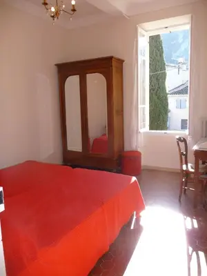 a bedroom with a red bed and a large window at Maison Daumas Billard Français et Piscine in Robion en Luberon