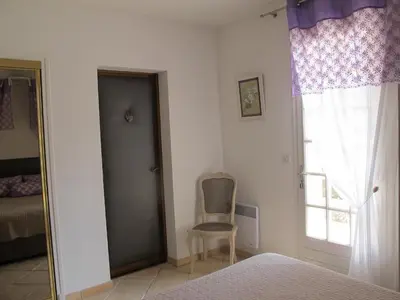 a bedroom with a bed and a chair next to a window at L'Oustau de Bigatié in Lambesc