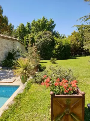 a garden with red flowers next to a swimming pool at Mas au Cœur de La Provence & SPA in Saint-Cannat