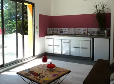 a kitchen with white cabinets and a table in a room at Les cabanes de Vallis Clausa in Saumane-de-Vaucluse