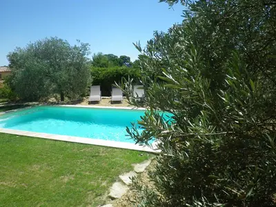 a swimming pool in a yard with two lawn chairs at La mordorée in La Motte-dʼAigues