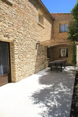 a patio with a table and a brick building at La Caprine in Gordes