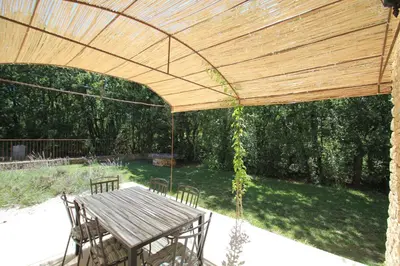 a wooden pergola with a wooden table and chairs at La Caprine in Gordes