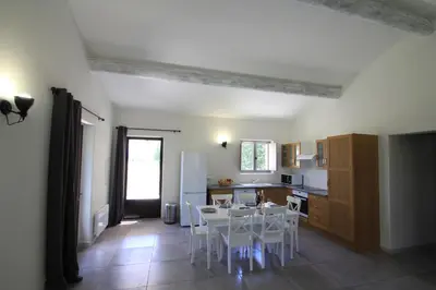 a kitchen with a table and white chairs in it at La Caprine in Gordes