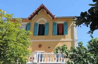 a yellow house with green shutters and a porch at 1001 Ocres in Apt