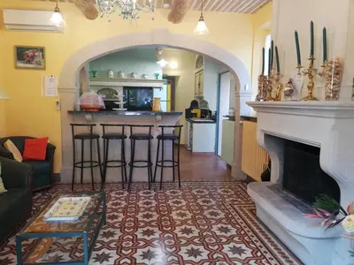 a living room with a fireplace and a kitchen at Gîte familial de charme, piscine chauffée en Provence in Le Thor