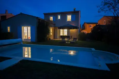 a swimming pool in front of a house at night at Lagrange Vacances - Le Clos Savornin in Saint-Saturnin-les-Apt