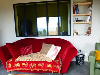 a red couch in a room with a window at Maison Itzé in Saint-Saturnin-les-Apt