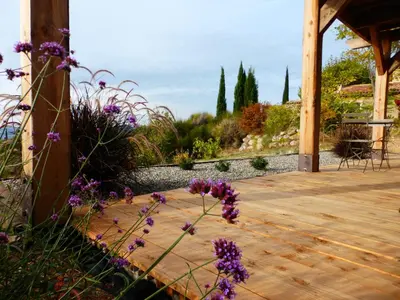 a wooden deck with purple flowers in a garden at Maison Itzé in Saint-Saturnin-les-Apt