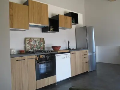 a kitchen with wooden cabinets and a refrigerator at Maison Itzé in Saint-Saturnin-les-Apt