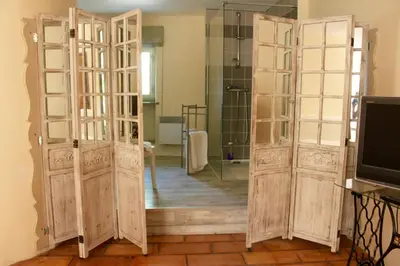a bathroom with two wooden doors and a mirror at Mas de la Gonnette in Venasque