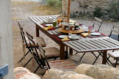 a wooden table with chairs and food on it at Mas de la Gonnette in Venasque