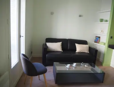 a living room with a black couch and a table at APPART AIX MAZARIN in Aix-en-Provence