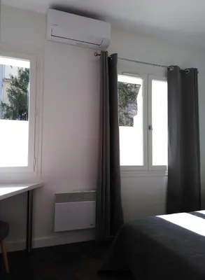 a bedroom with a bed and two windows at APPART AIX MAZARIN in Aix-en-Provence