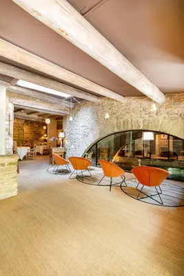 a lobby with orange chairs and a stone wall at La Prévôté - Luxury Chambres d'hôtes & Gastronomic Restaurant in LʼIsle-sur-la-Sorgue