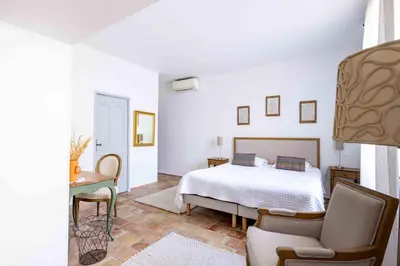 a white bedroom with a bed and a chair at La Prévôté - Luxury Chambres d'hôtes & Gastronomic Restaurant in LʼIsle-sur-la-Sorgue