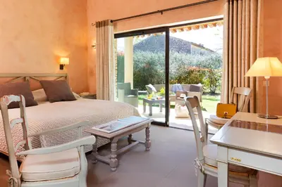 a bedroom with a bed and a table and chairs at Hôtel Carcarille Restaurant Le C in Gordes