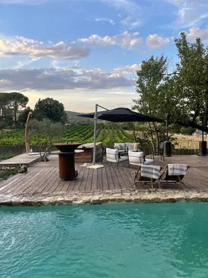 a patio with chairs and an umbrella next to a pool at La Belugue in Beaumont-de-Pertuis