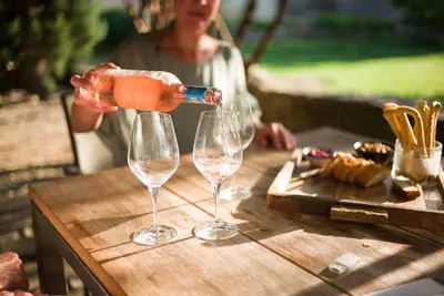 a woman pouring wine into two wine glasses on a table at La Belugue in Beaumont-de-Pertuis